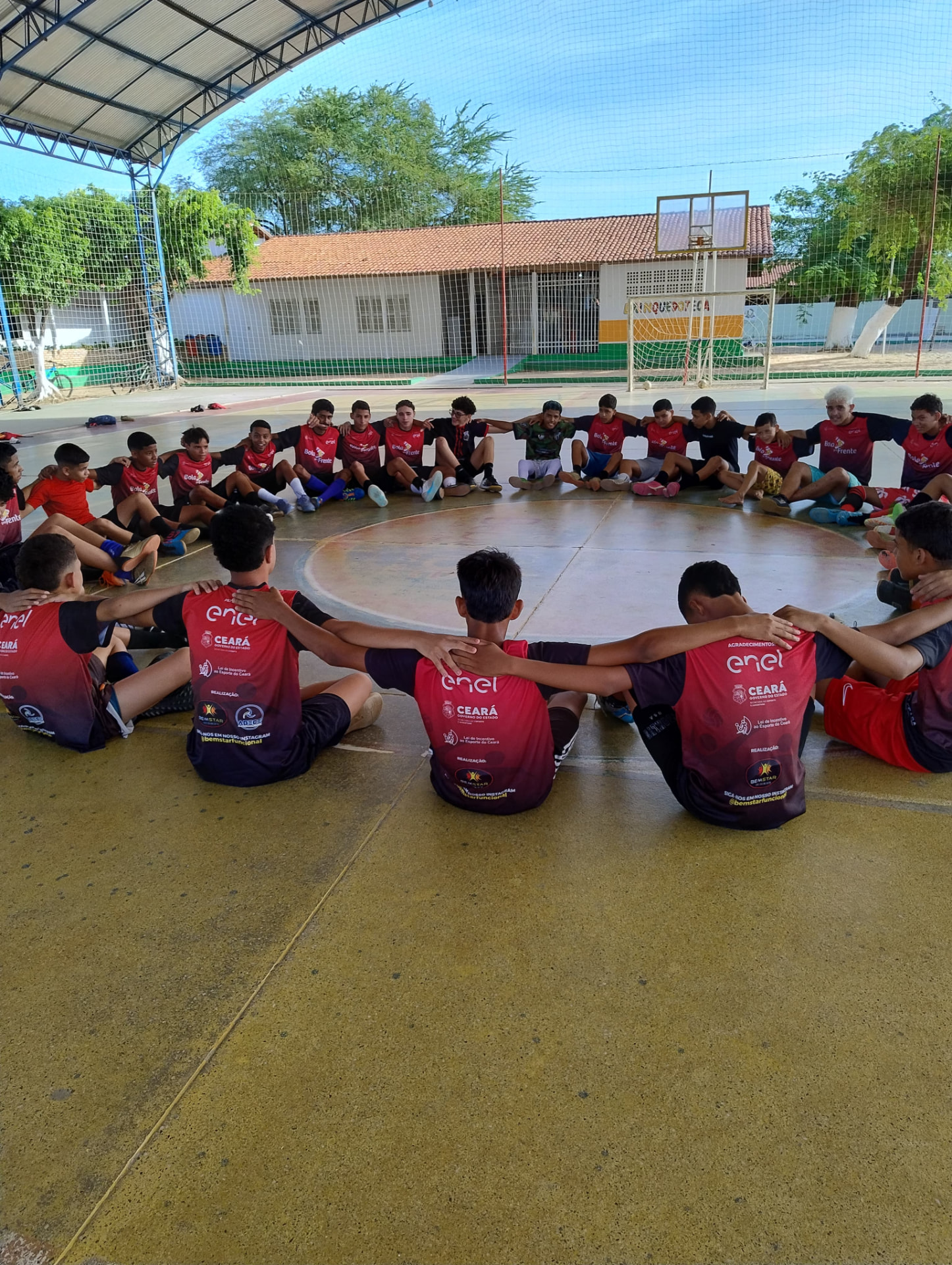 Crianças em roda de alongamento na quadra