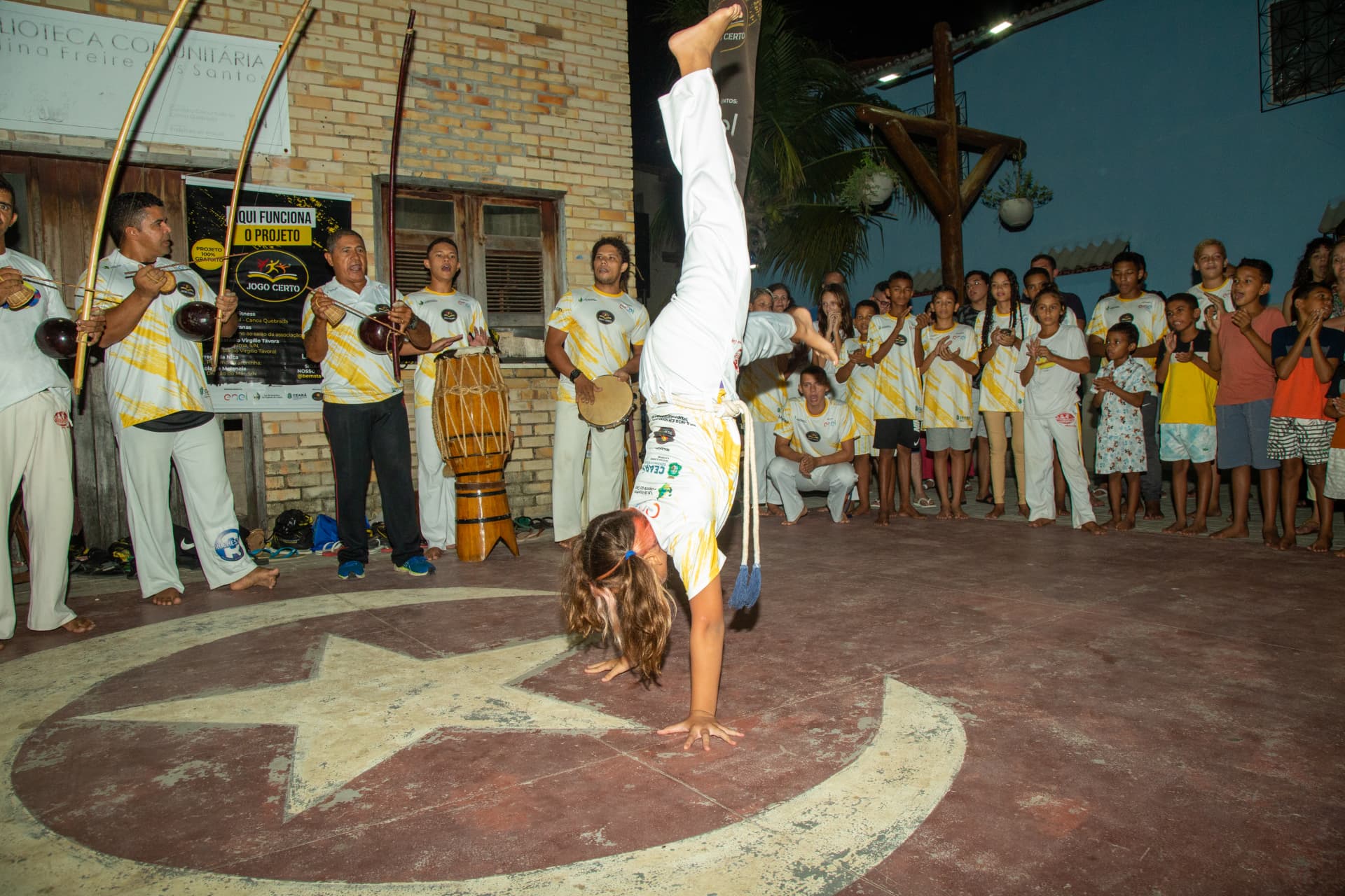 Apresentação de capoeira com acrobacia diante do grupo